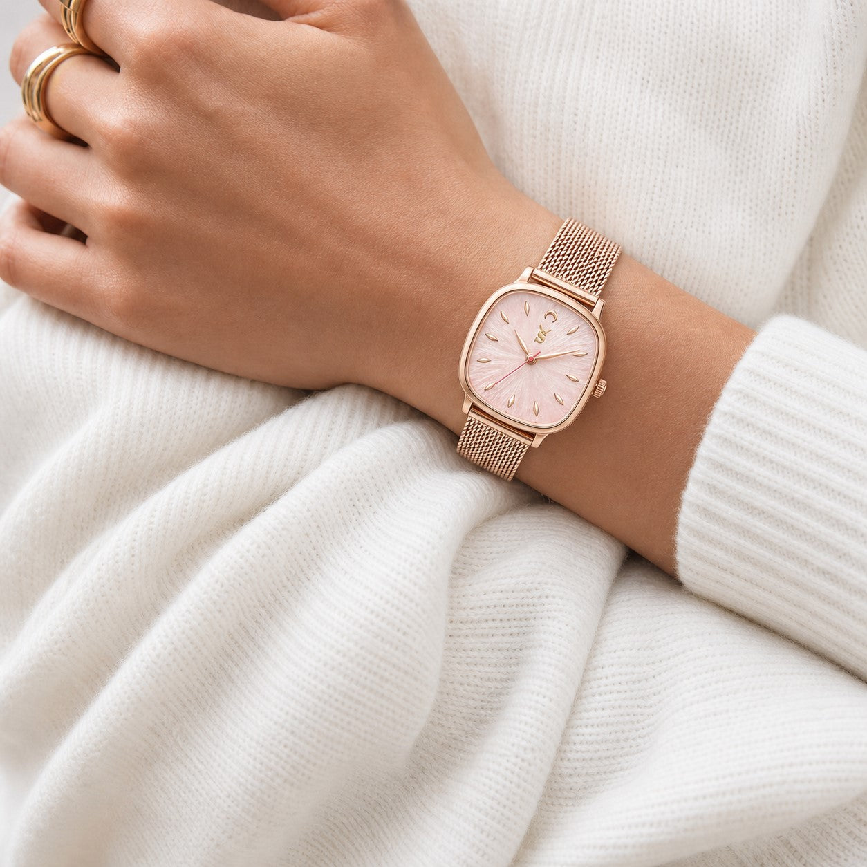 Rose gold watch on a wrist with a white sweater background