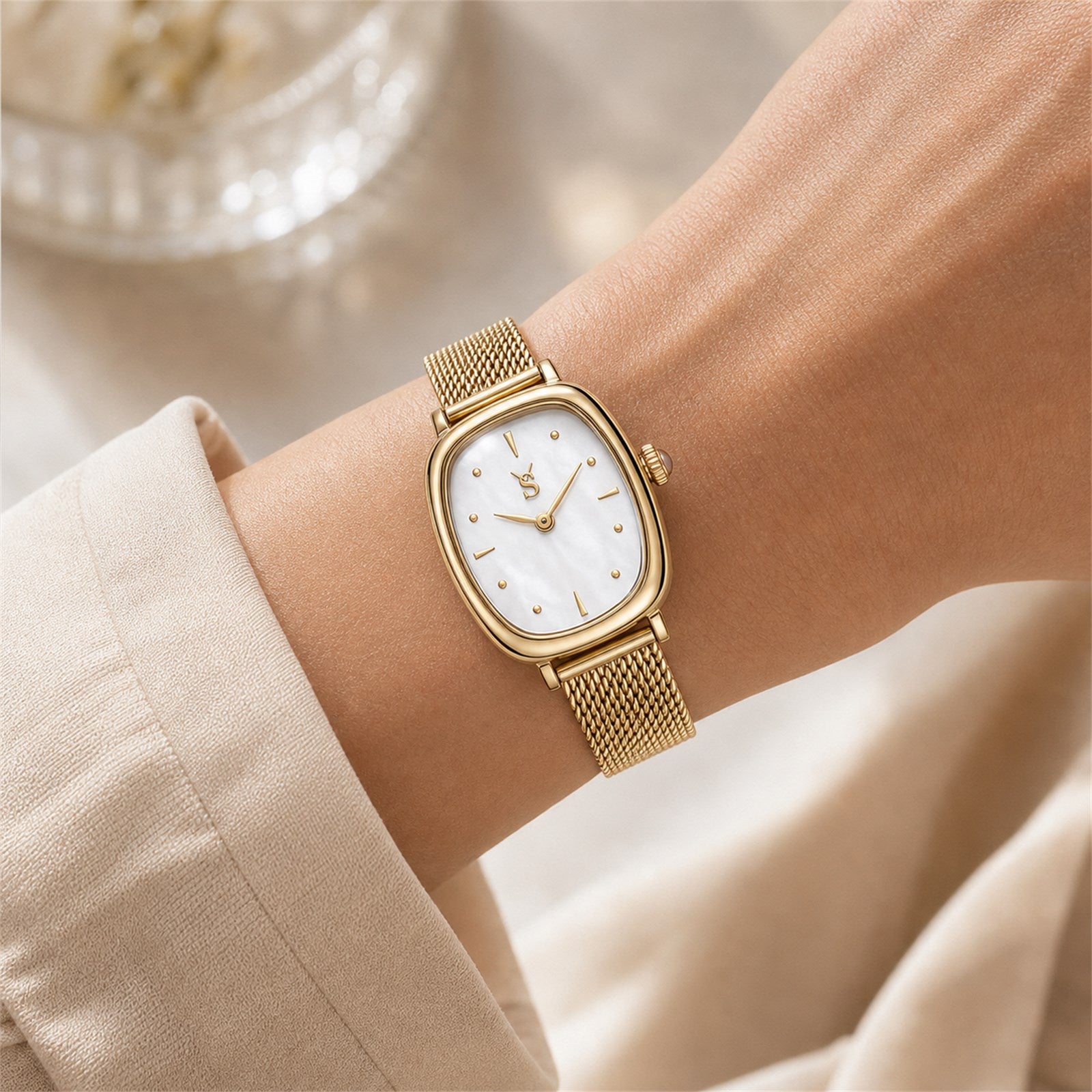 Close up of a woman wearing the elegant Savwatch gold mesh watch with a mother of pearl dial, styled with a classic beige blouse.