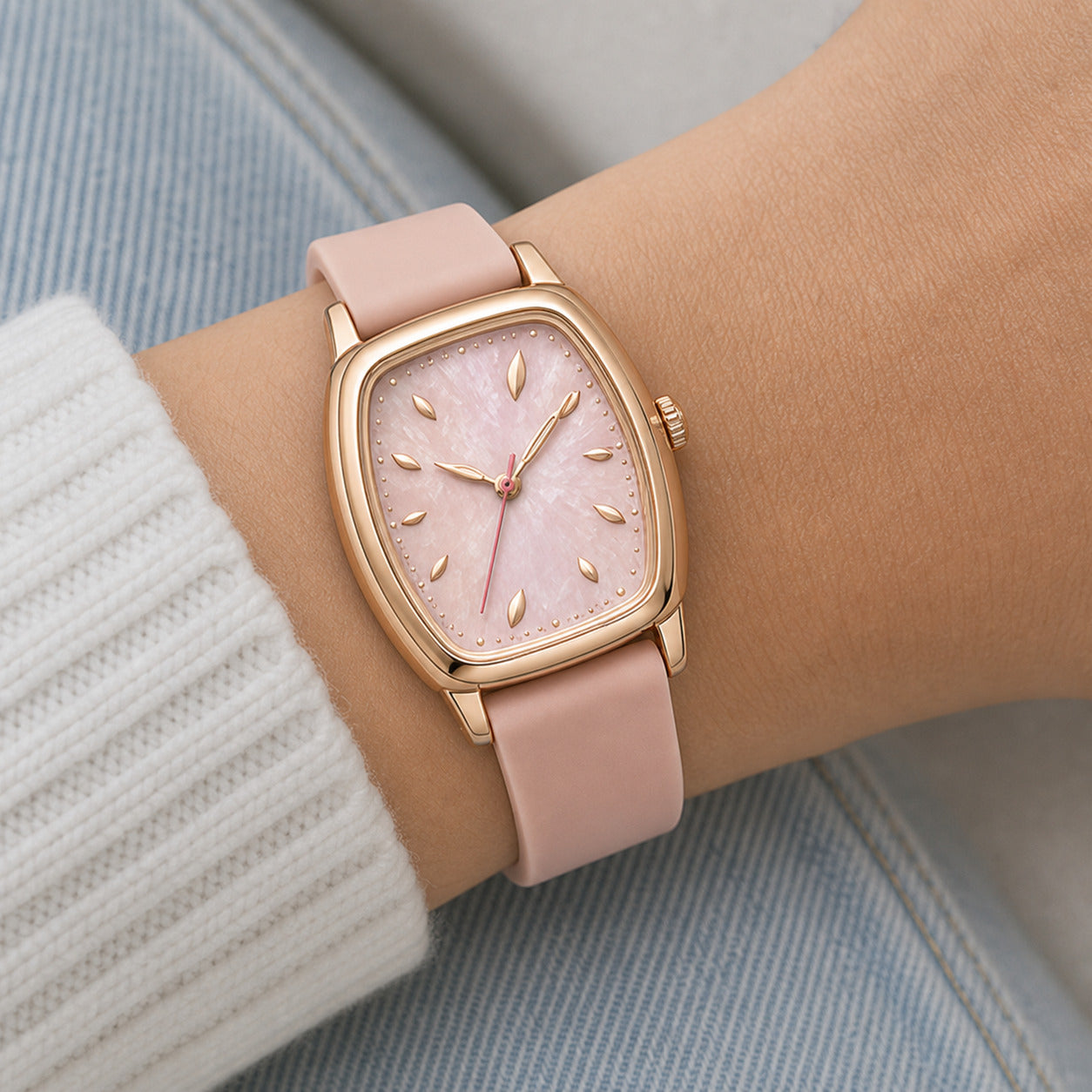 Pink watch with rose gold case on a wrist against a light background