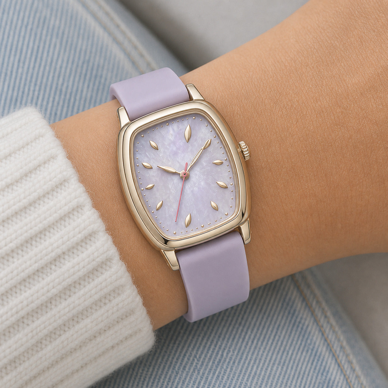 Watch with a purple strap and gold case on a wrist, against a neutral background
