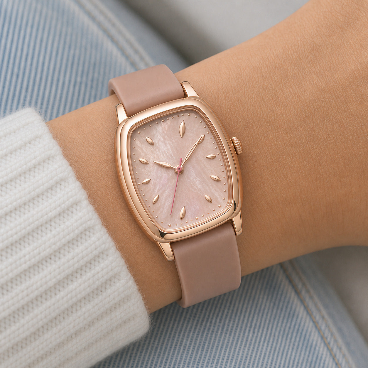 Rose gold watch with beige strap on wrist against a light background