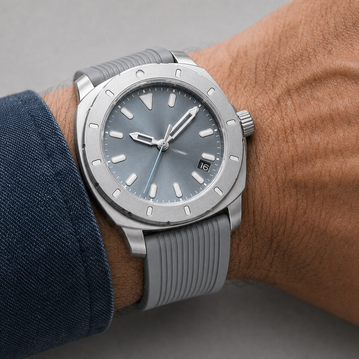 Silver watch with gray strap on a wrist against a neutral background