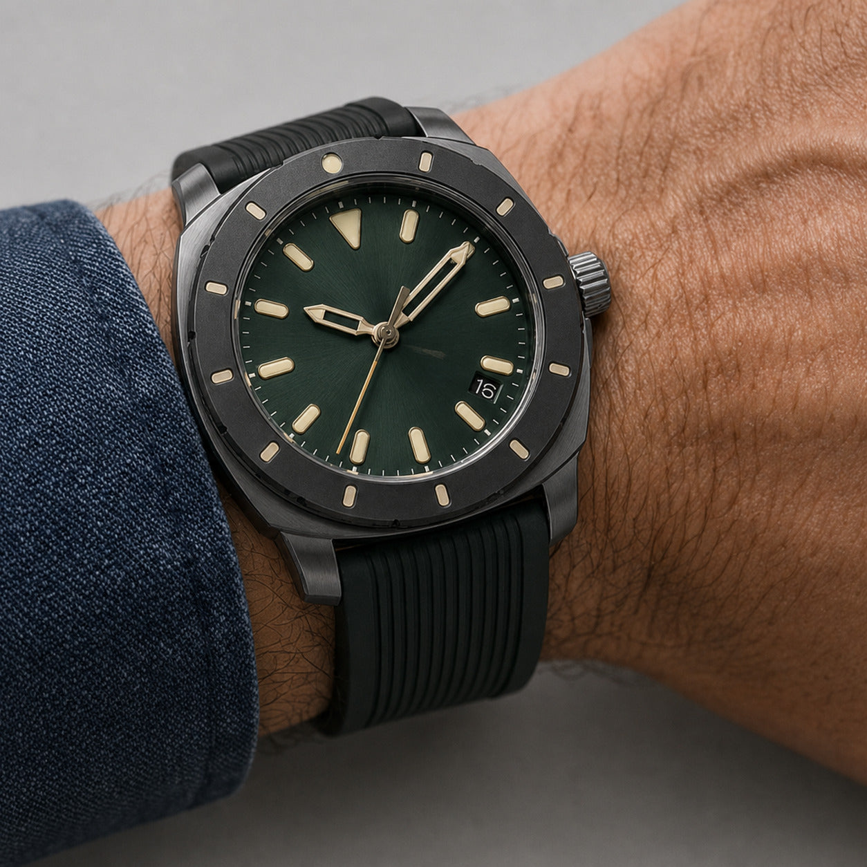 Watch with a green dial and black strap on a wrist against a gray background