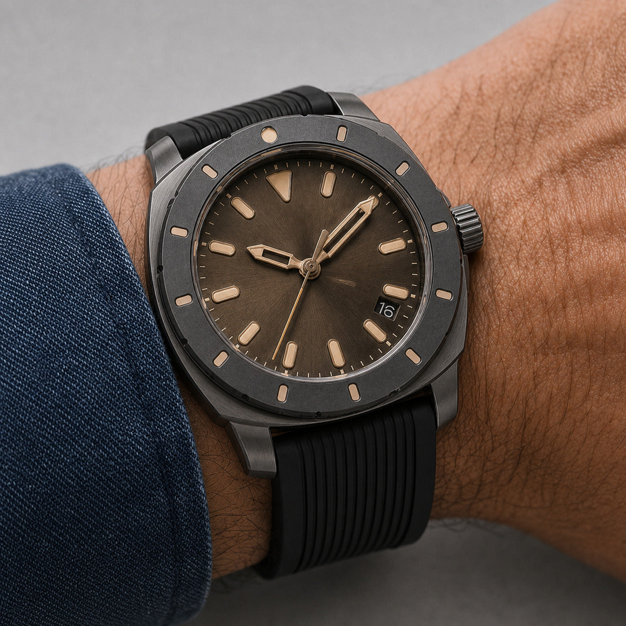Wrist wearing a dark wristwatch with a brown dial on a neutral background